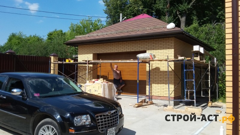 Построить гараж из газосиликатных блоков с облицовкой кирпичом. Фундамент плита, площадка под заезд, забор из кирпичных столбов и профнастила с откатными воротами